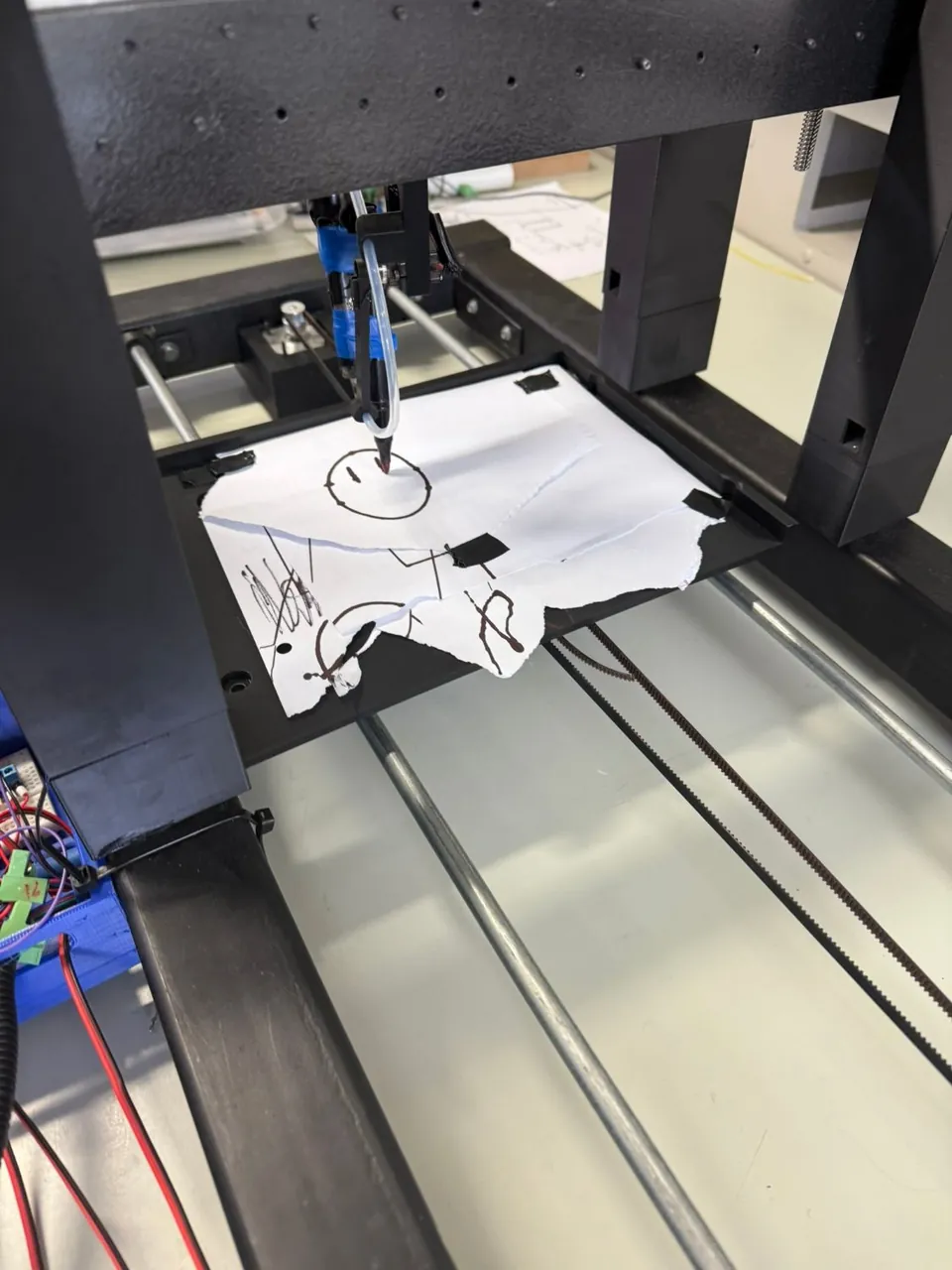 The machine's pen drawing on a sheet of paper laid on its bed.