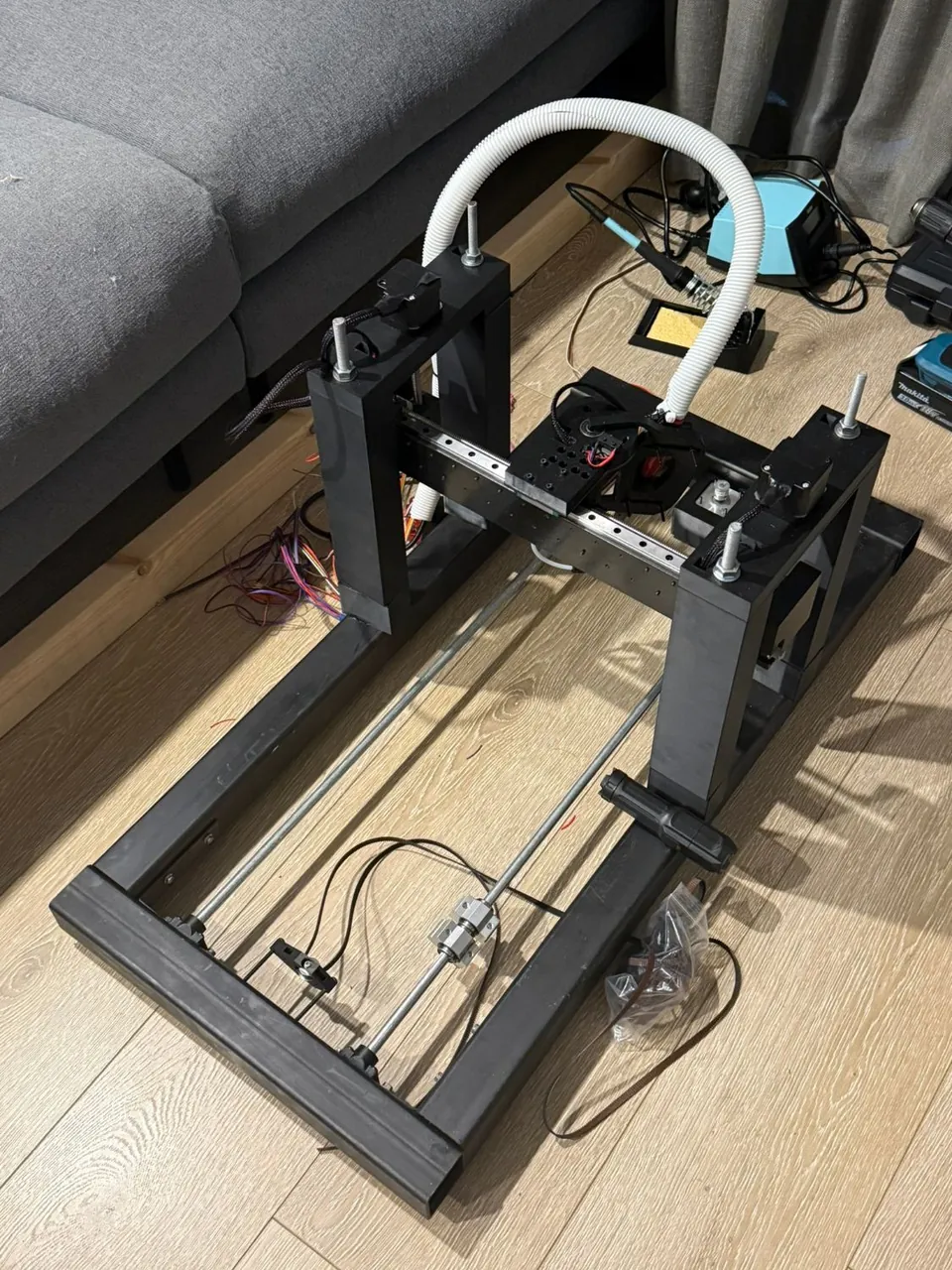 The CNC machine from the side, with a soldering iron and tools on the floor beside it.