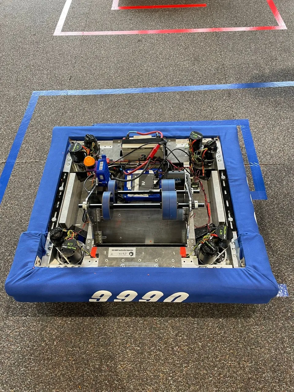 A robot with a blue bumper numbered 9990, seen from above on the field.